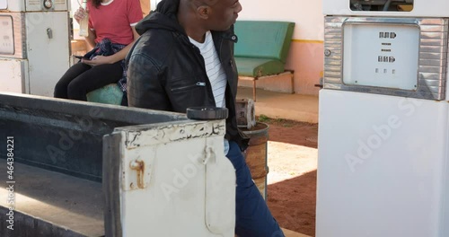 Diverse man and woman using fuel pump filling up truck at petrol station photo