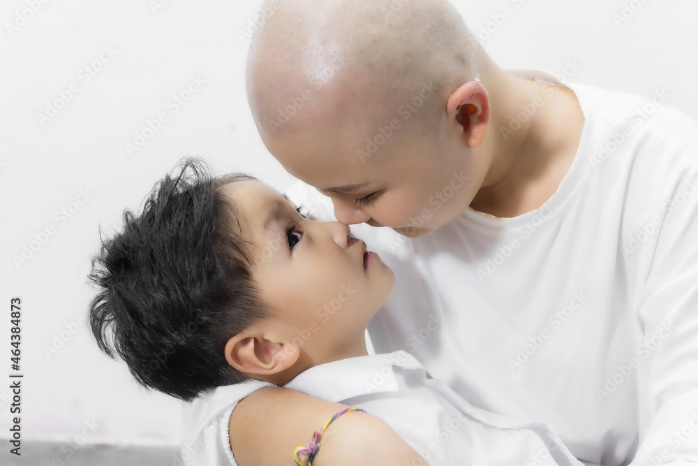 Young adult female cancer patient spending time with son at home, relaxing on the couch. Cancer and family support concept. Young adult female cancer patient spending time with son at home, relaxing on the couch. Cancer and family support concept.