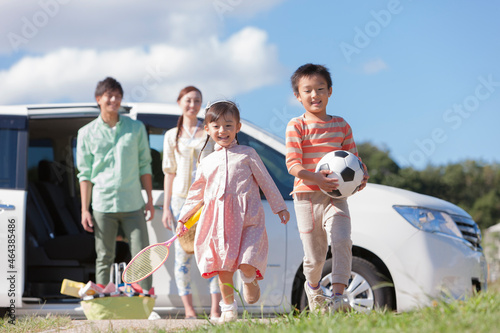 車から降りて走るきょうだいと見守る夫婦