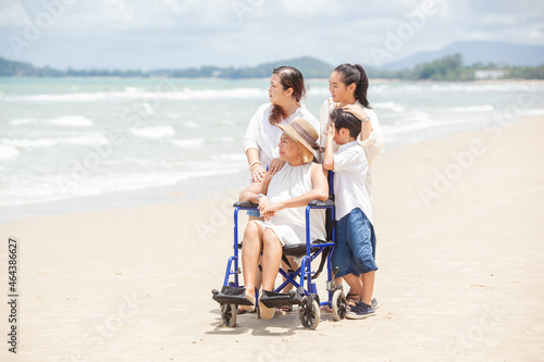 Disabled woman asia in a wheelchair with his family on the beach. Wheelchair woman sitting relax on the beach. family relax concept