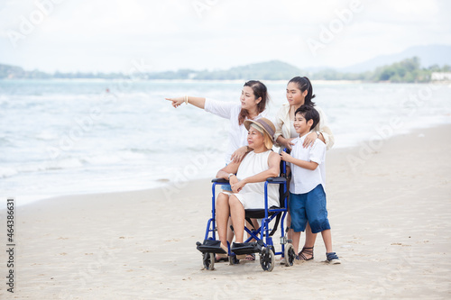 Disabled woman asia in a wheelchair with his family on the beach. Wheelchair woman sitting relax on the beach. family relax concept