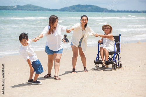 Disabled woman asia in a wheelchair with his family on the beach. Wheelchair woman sitting relax on the beach.  family relax concept © nikomsolftwaer