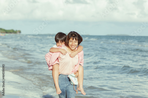 Young happy beautiful mother and her daughter having fun on the beach. Young family asian on vacation have a lot of fun