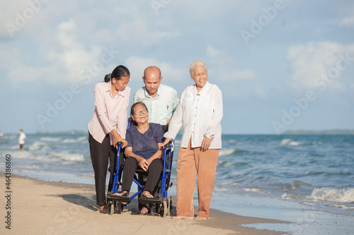 Disabled woman asia in a wheelchair with his family on the beach. Wheelchair woman sitting relax on the beach.  family relax concept