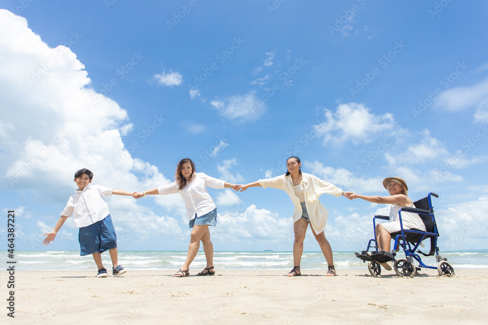 Disabled woman asia in a wheelchair with his family on the beach. Wheelchair woman sitting relax on the beach. family relax concept Disabled woman asia in a wheelchair with his family on the beach. Wheelchair woman sitting relax on the beach. family relax concept