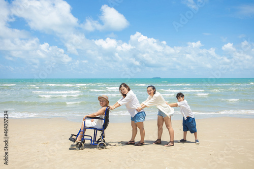 Disabled woman asia in a wheelchair with his family on the beach. Wheelchair woman sitting relax on the beach. family relax concept