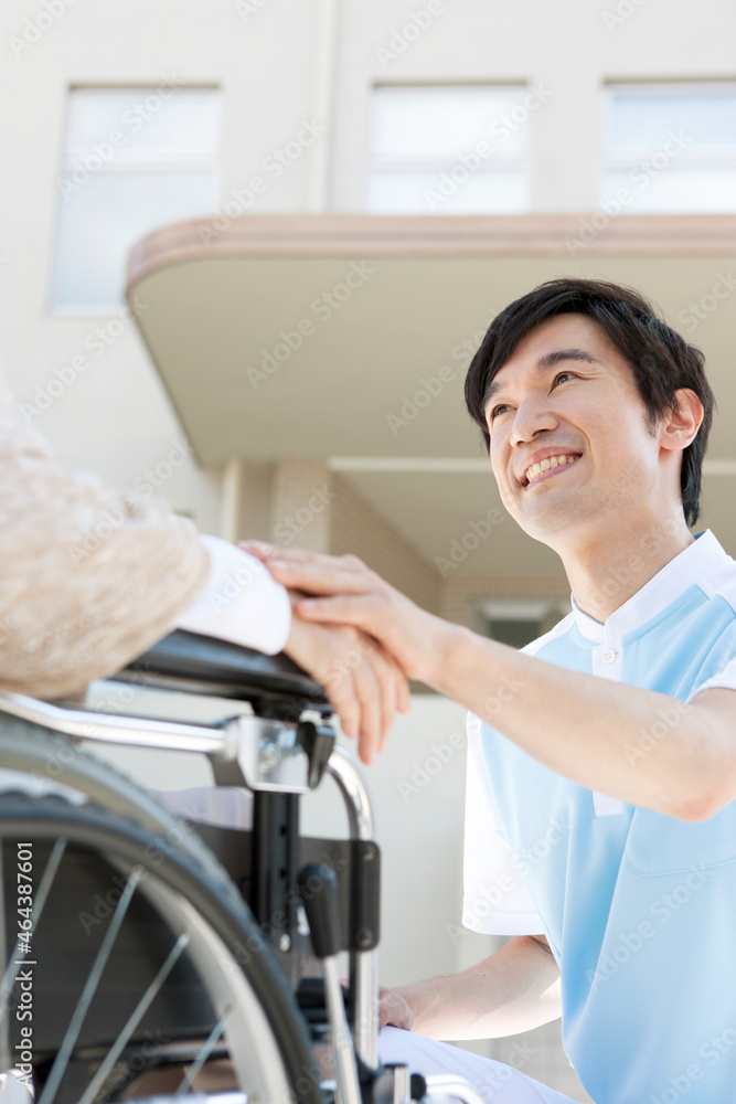 車いすに乗った中高年女性に寄り添う介護士 車いすに乗った中高年女性に寄り添う介護士