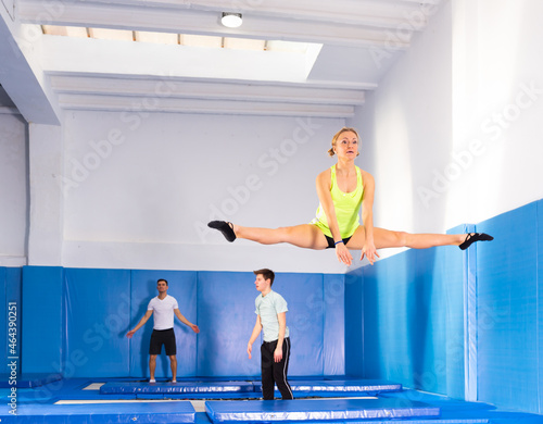 Athletic young woman training jumping movements in indoor trampolines center © JackF