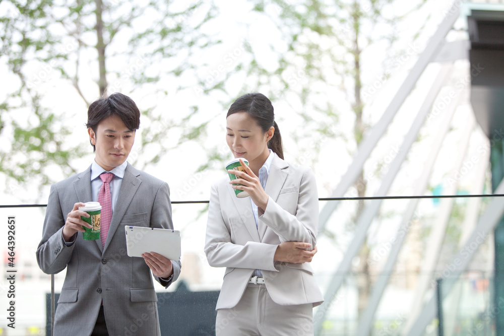 タブレットPCを見て話すビジネスマン2人