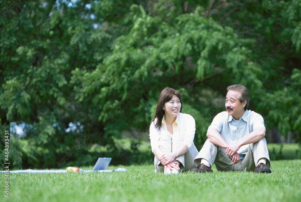 芝生に座る中高年夫婦 芝生に座る中高年夫婦