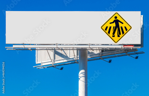 Billboard in blue sky with pedestrian crossing sign.