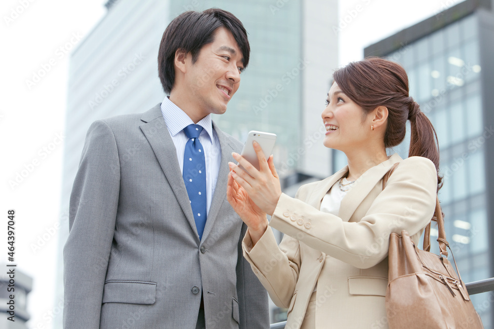 スマートフォンを持つビジネスマンとビジネスウーマン