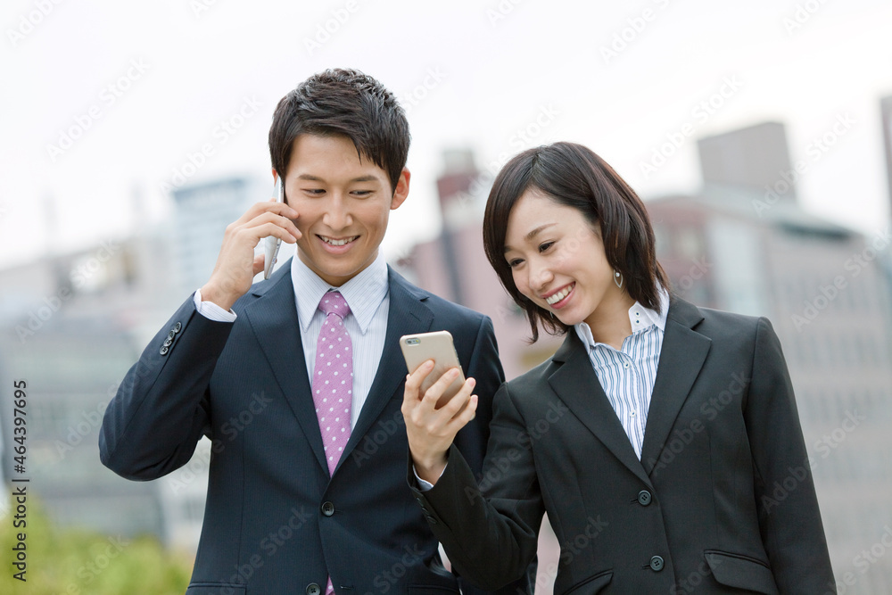 スマートフォンを見るビジネスマンとビジネスウーマン