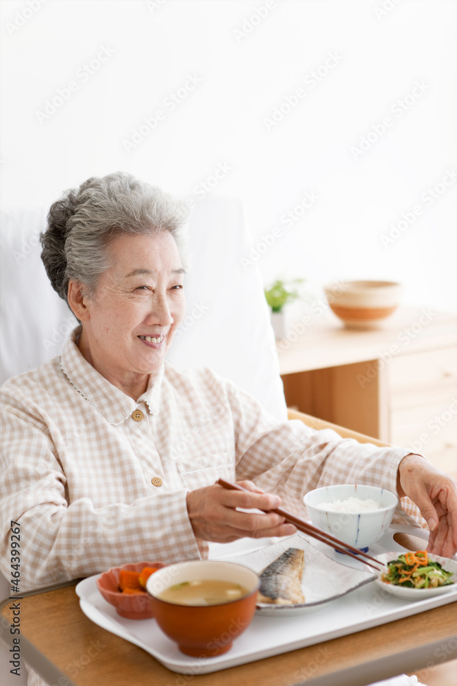 介護ベッドで食事をするシニア女性 介護ベッドで食事をするシニア女性