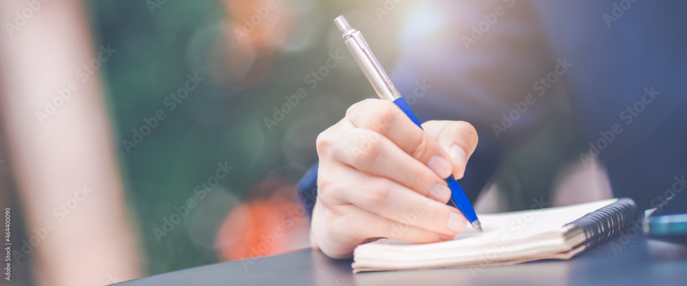 Business woman hand writing on a notepad with a pen in the office.