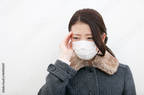 こめかみを押さえる女性