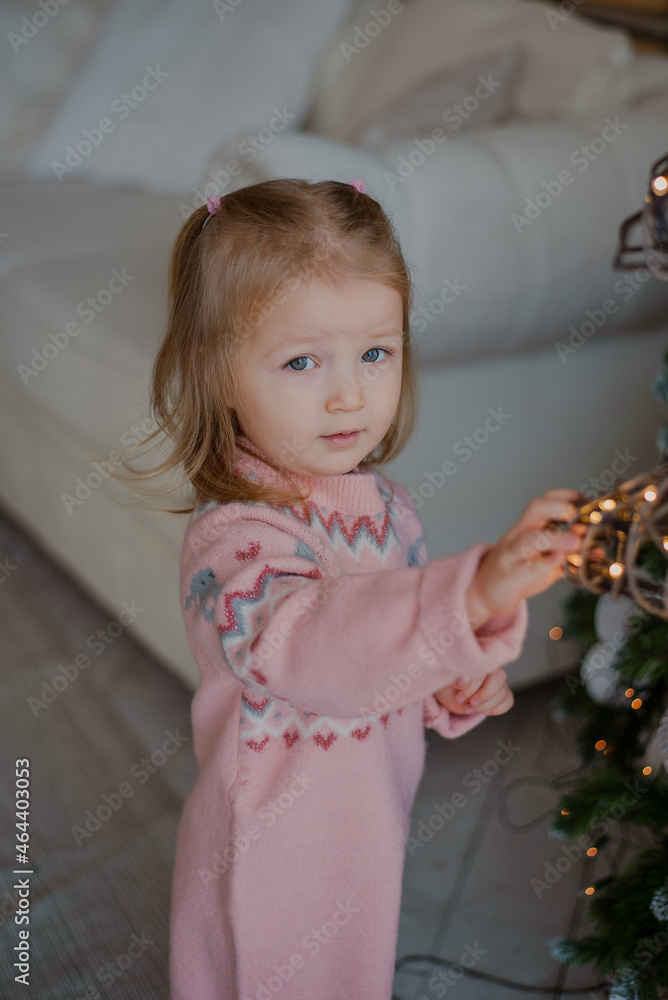 Portrait of a charming little girl decorating a Christmas tree. Christmas 2022. Portrait of a charming little girl decorating a Christmas tree. Christmas 2022.