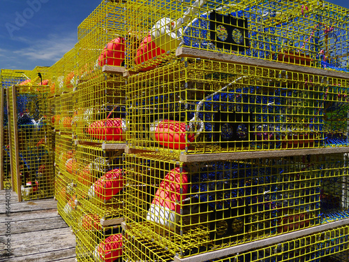 Bright Yellow lobster pots or lobster traps sit with red and white floats on a Maine Dock photo