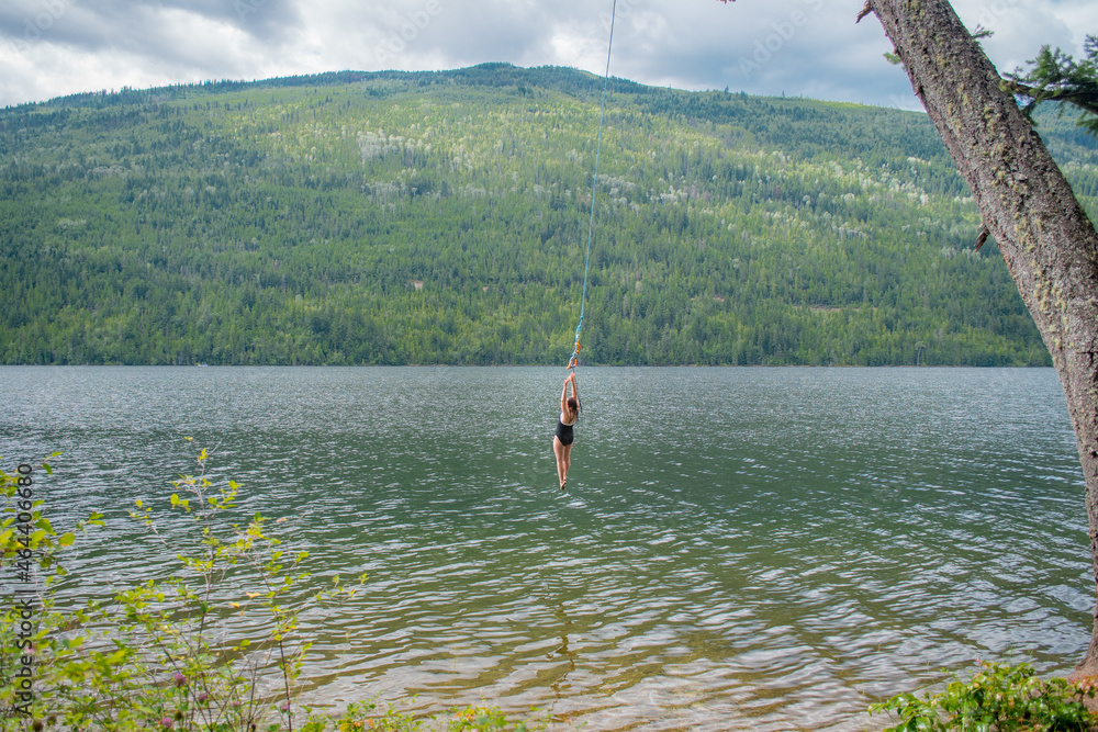 A person jumps into water from jump swing. Adams Lake, BC, Canada. Vacation vibes on the sunny day in the north
