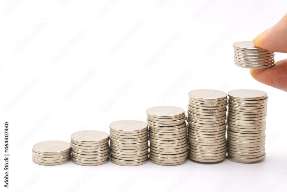 Business, Saving and Financial Concept. Closeup of man finger holding stack of coins and put to top of stack of silver coins on white background. Business, Saving and Financial Concept. Closeup of man finger holding stack of coins and put to top of stack of silver coins on white background.