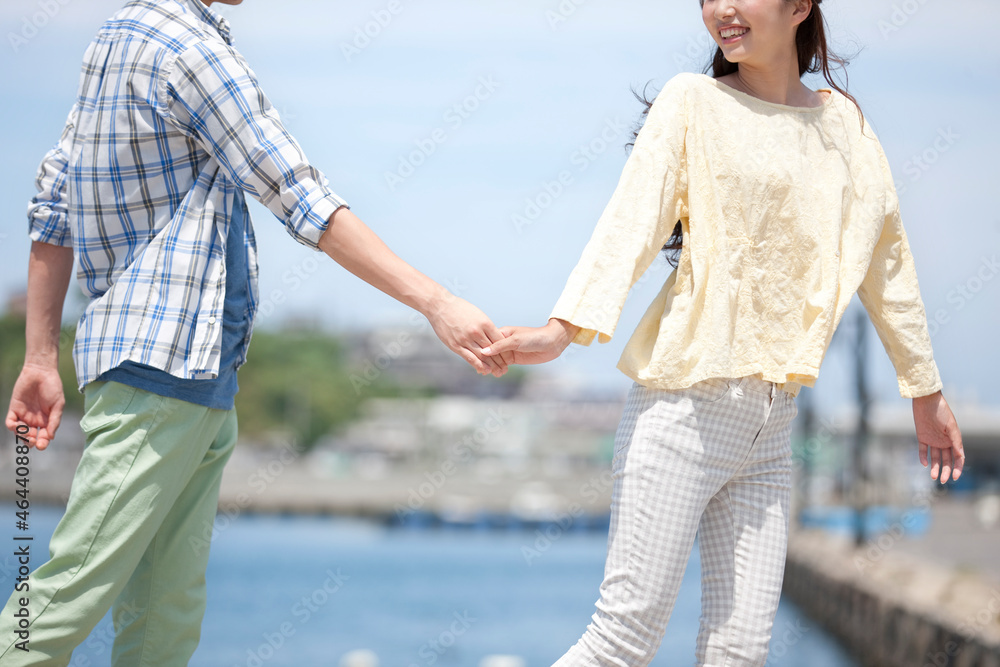 海岸で手をつなぐカップル