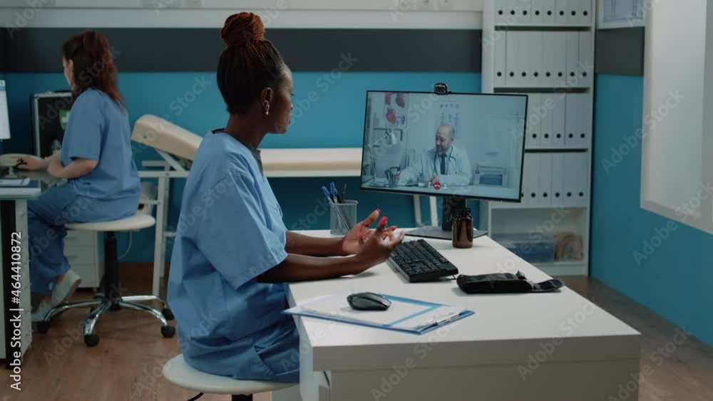 Nurse talking to doctor on video call connection in cabinet. Medical assistant using online video conference on computer for professional advice with healthcare and consultation Nurse talking to doctor on video call connection in cabinet. Medical assistant using online video conference on computer for professional advice with healthcare and consultation