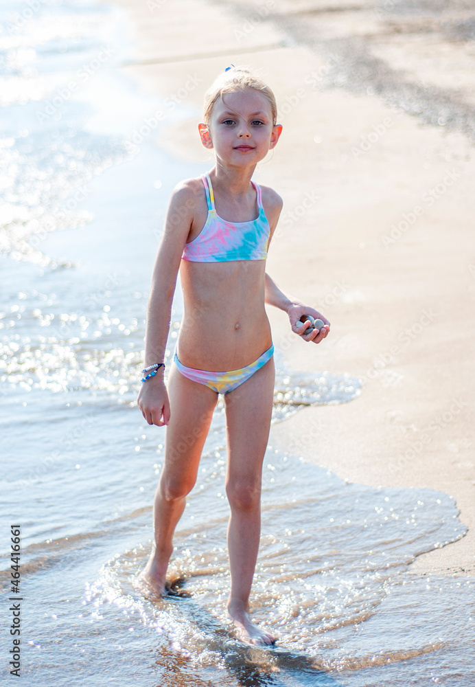 Little girl playing on the beach by the sea Stock Photo | Adobe Stock