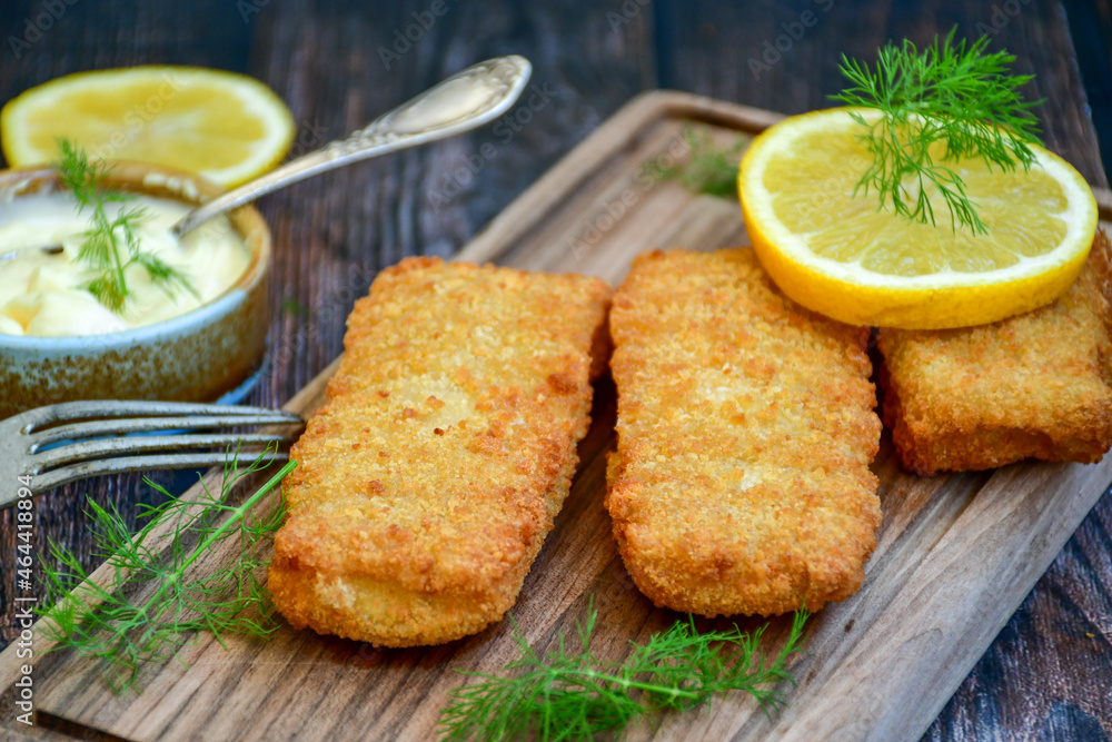 Close up of Crispy breaded deep fried fish fingers with breadcrumbs served with remoulade sauce and lemon Cod Fish Nuggets on rustic wood table background Close up of Crispy breaded deep fried fish fingers with breadcrumbs served with remoulade sauce and lemon Cod Fish Nuggets on rustic wood table background