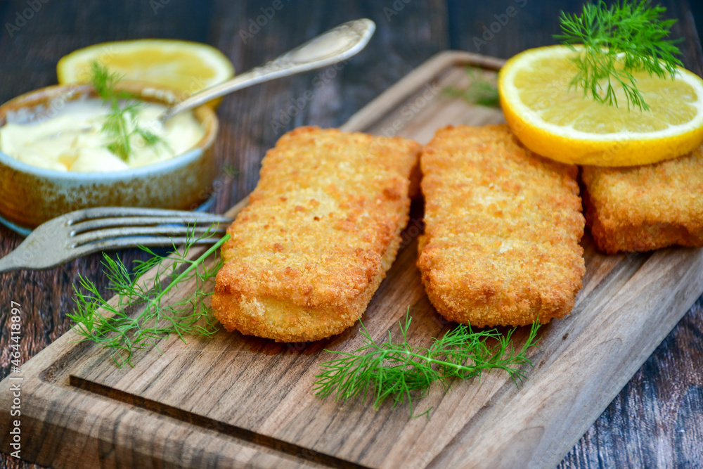 Close up of Crispy breaded deep fried fish fingers with breadcrumbs served with remoulade sauce and lemon Cod Fish Nuggets on rustic wood table background Close up of Crispy breaded deep fried fish fingers with breadcrumbs served with remoulade sauce and lemon Cod Fish Nuggets on rustic wood table background