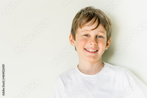 Portrait of smiling 8-year-old caucasian boy wearing a white t-shirt with copy space