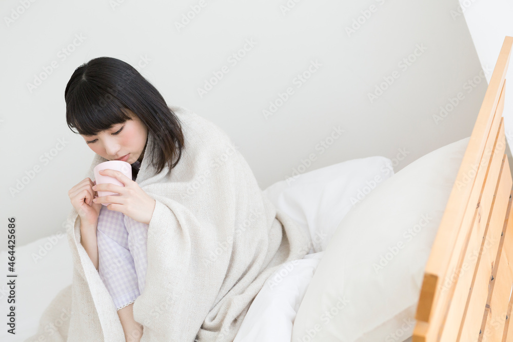 ブランケットにくるまって飲み物を飲む女性 ブランケットにくるまって飲み物を飲む女性