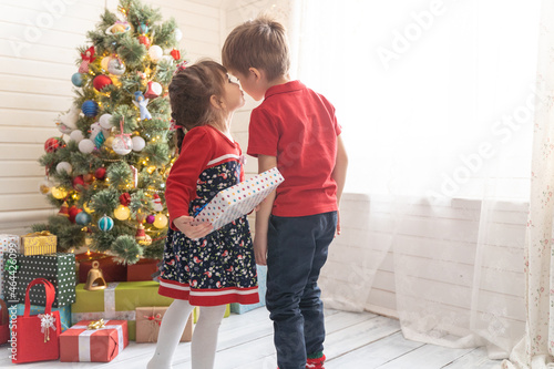 Boy gives a Christmas present to a girl in a bright sunny room