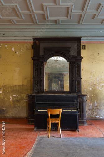 A beautiful antique mirror in a wooden frame and an old black piano in the interior of the ceremonial hall in Sharovsky castle, Ukraine