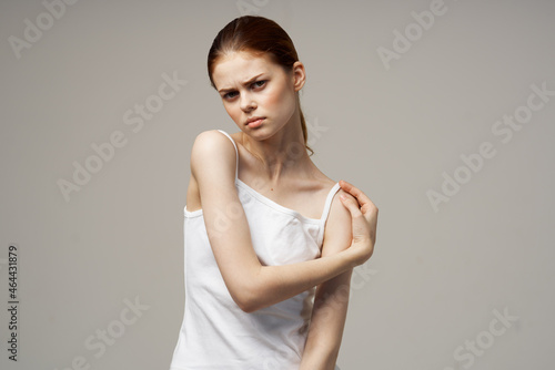 woman in white t-shirt rheumatism pain in the neck health problems light background