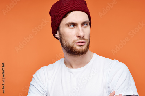 man in a white t-shirt and a hat tattoo on his arms orange background