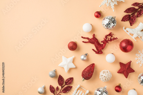 Top view photo of composition white silver and red christmas tree decorations snowflakes stars disco balls cone deer small ice skates sleigh and sprigs on isolated beige background with copyspace