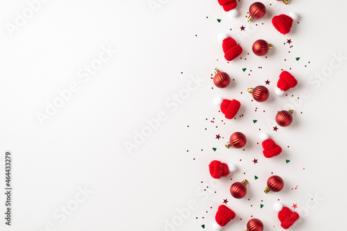 Top view photo of row composition red christmas tree decorations small balls bobble hats and multicolor confetti on isolated white background with empty space