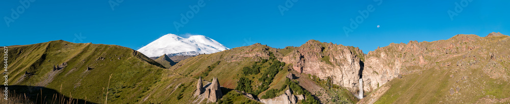 Kabardino-Balkaria, Russia. Panoramic view of mount Elbrus and Sultan-Su waterfall with clear blue sky. Beautiful landscape of caucasus mountains at autumn season.