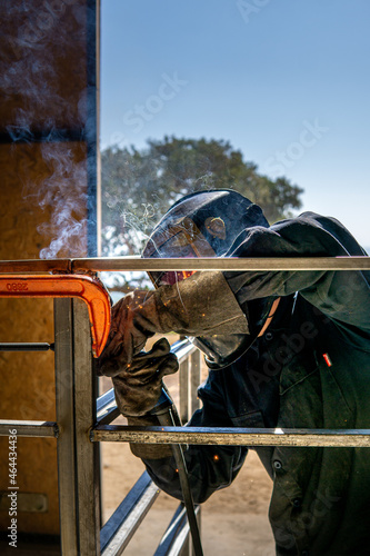 Worker with protective mask welding metal cage in kibbutz ravid, israel. cooperative work in modern socialist lifestyle.