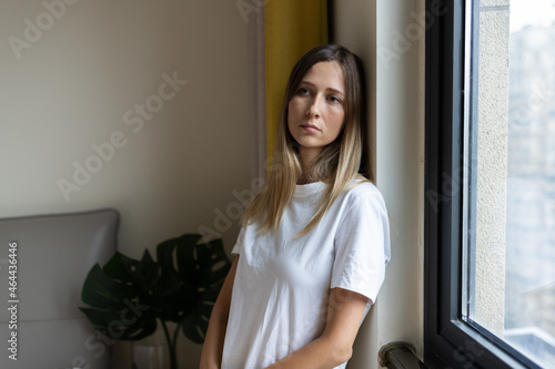 Unhappy young caucasian woman with blonde hair thinking about bad relationships problems, break up with boyfriend. Worried millennial girl standing in bedroom near window alone at home, suffering from © Алина Бузунова