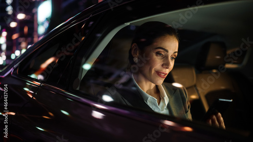 Billede på lærred Beautiful Businesswoman is Commuting from Office in a Backseat of Her Luxury Car at Night