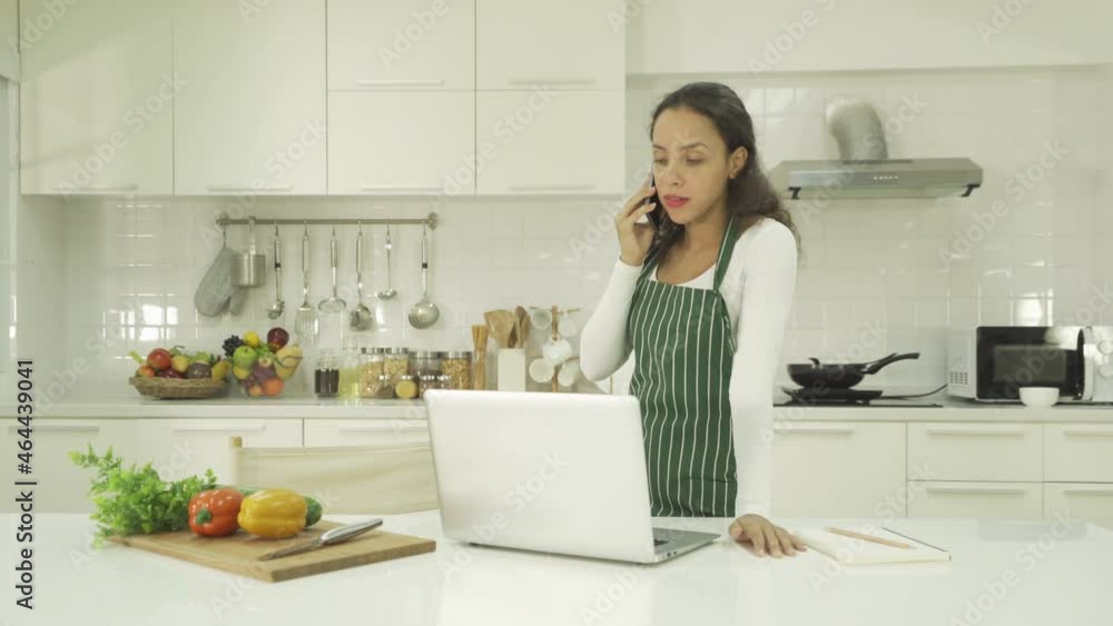 Relax happy latin young businesswoman. People talking on smartphone on social media internet and using a computer laptop notebook technology device in kitchen at home. Lifestyle Relax happy latin young businesswoman. People talking on smartphone on social media internet and using a computer laptop notebook technology device in kitchen at home. Lifestyle
