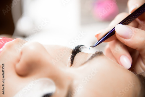 Beautiful young woman during eyelash extension  Close up.