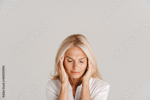 Mature blonde woman with headache rubbing her temples photo