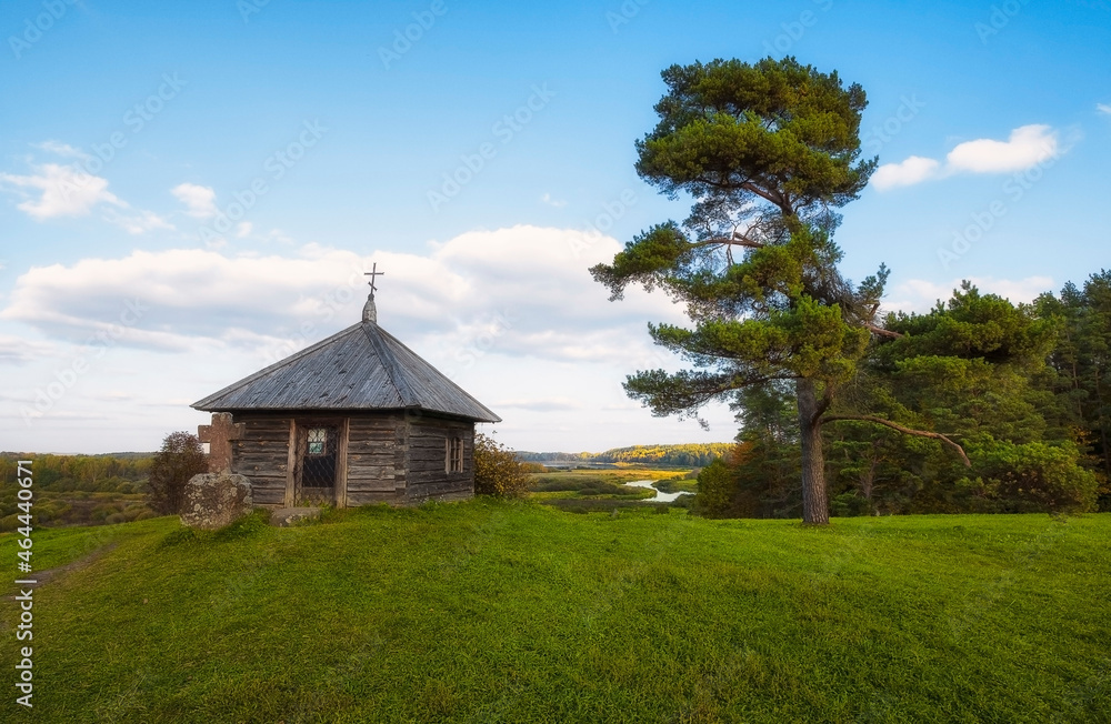 Obraz premium Rural landscape with views of the small chapel, forest and fields. Pushkin Hills with Savkina Gorka. Russia Pskov region in early autumn in evening