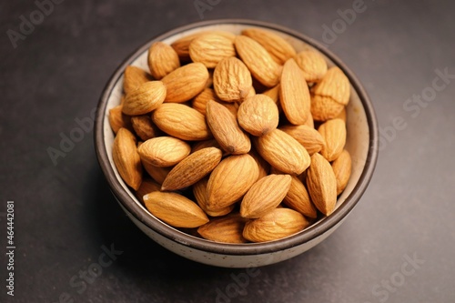 Almonds in white bowl on dark background. Almond Food or ingredient concept with copy space. Dry fruits background or festivals banners. Diwali gift concept.