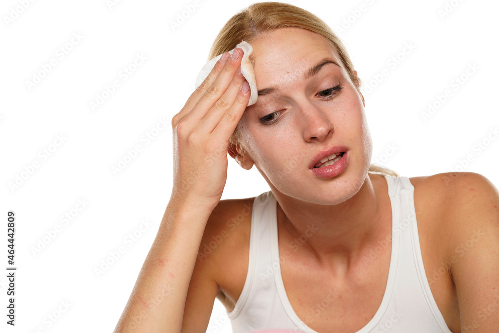 young blond woman with cleans her face with cotton pad young blond woman with cleans her face with cotton pad