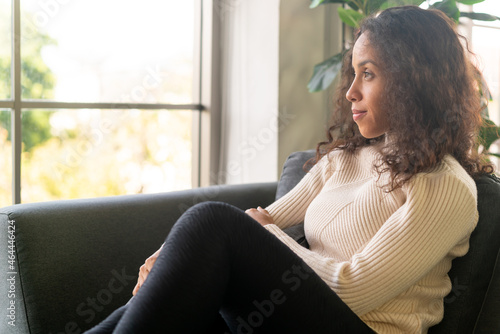 Latin woman smiling and sitting on sofa