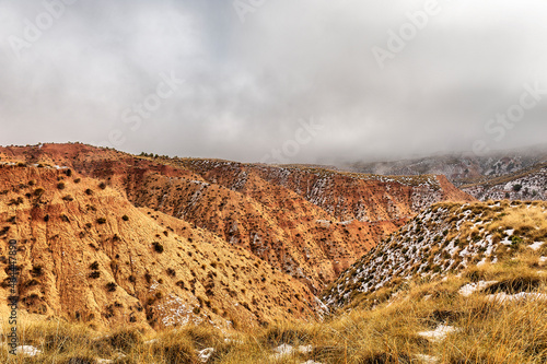 Brown mountains partially covered in snow against a dark blue sky. Granada Geopark. Gorafe Desert. photo