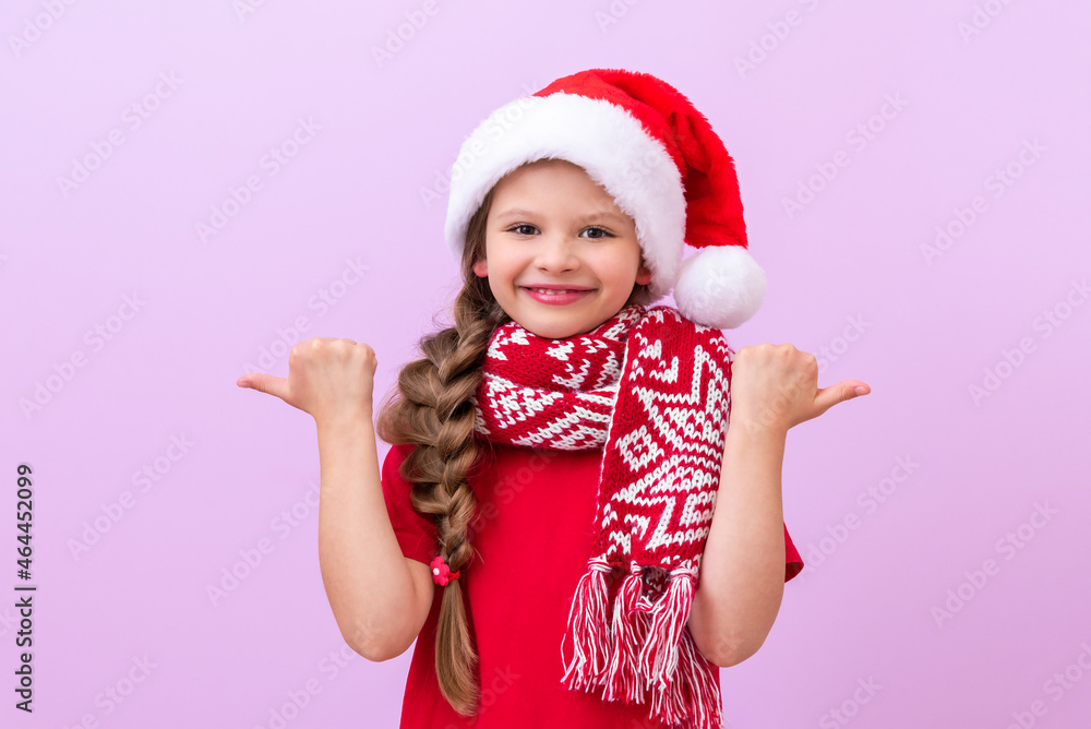 A joyful little girl in a New Year's hat points her fingers in different directions. A joyful little girl in a New Year's hat points her fingers in different directions.